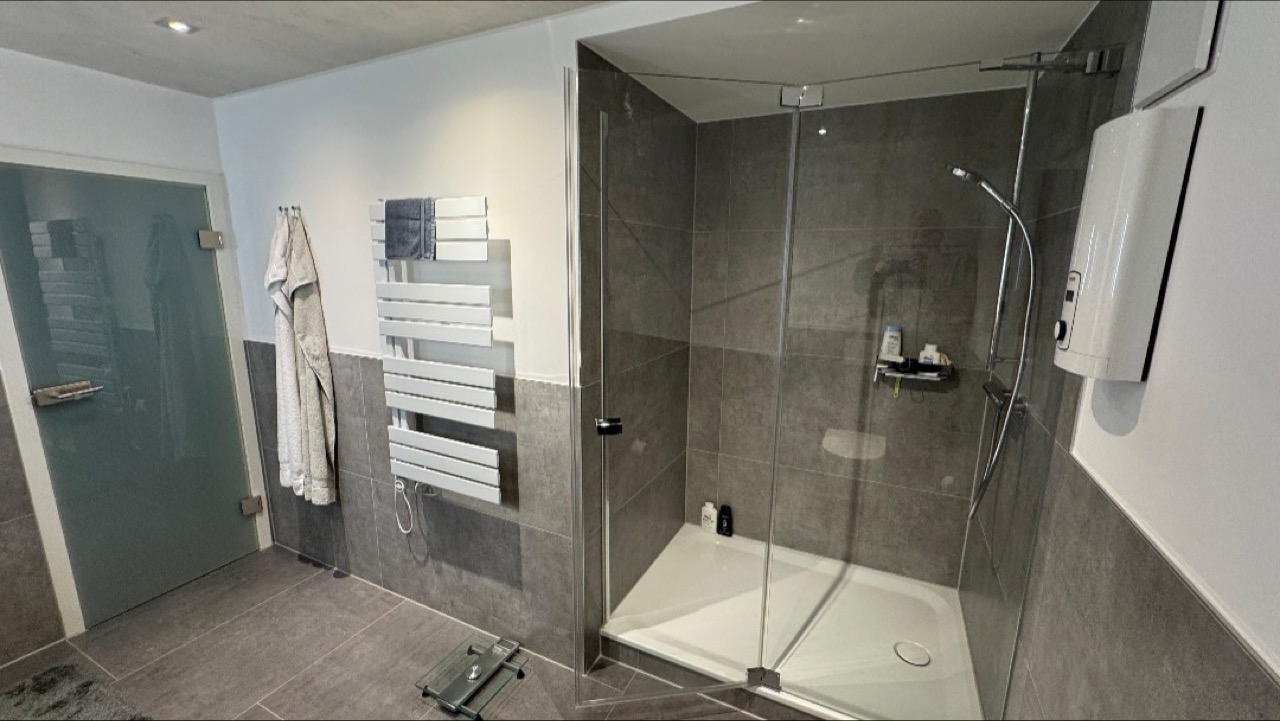 Dusche mit Glaswand neben einem Handtuchheizkörper
