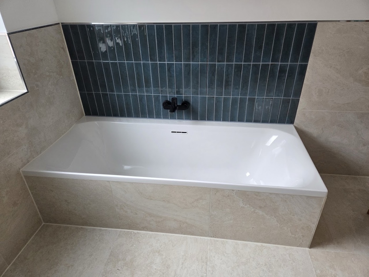 Badewanne mit dunkelblauen Wandfliesen