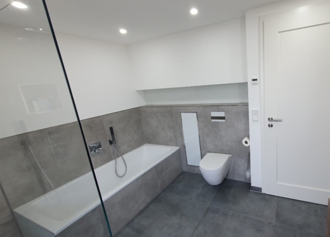Bad mit grauen Fliesen, Wanne und Wand-WC