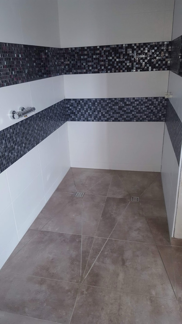 Raum mit Mosaik-Bordüre an der Wand und grauen Bodenfliesen
